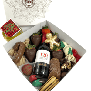 Deliciosa caja surtida con fresas, mendiants, bombones, galletas y botella de vino pequeña, perfecta para quienes aman los sabores navideños. Puedes personalizar la colilla.