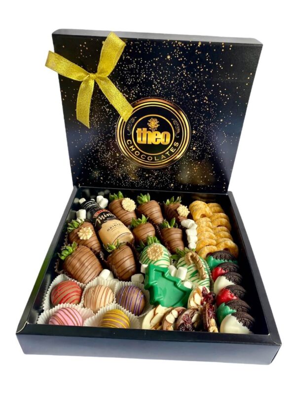 Caja con combinación de fresas cubiertas y decoradas con chocolatre, bombones, galletas, un arbolito de navidad en chocolate, mendiants y orejitas hojaldradas